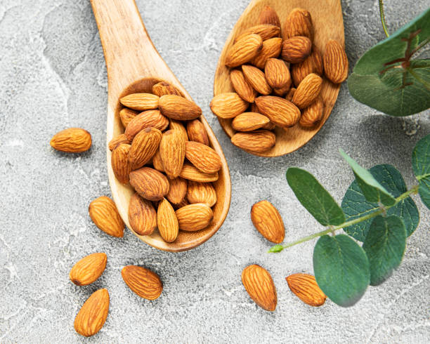 Almonds in brown spoons on concrete background Amandes