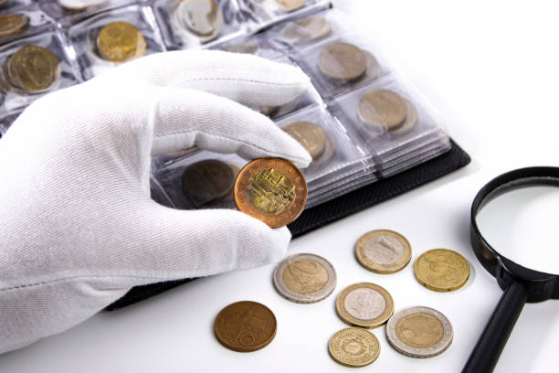 A collector in white gloves examines a coin, close-up. expertise numismatique